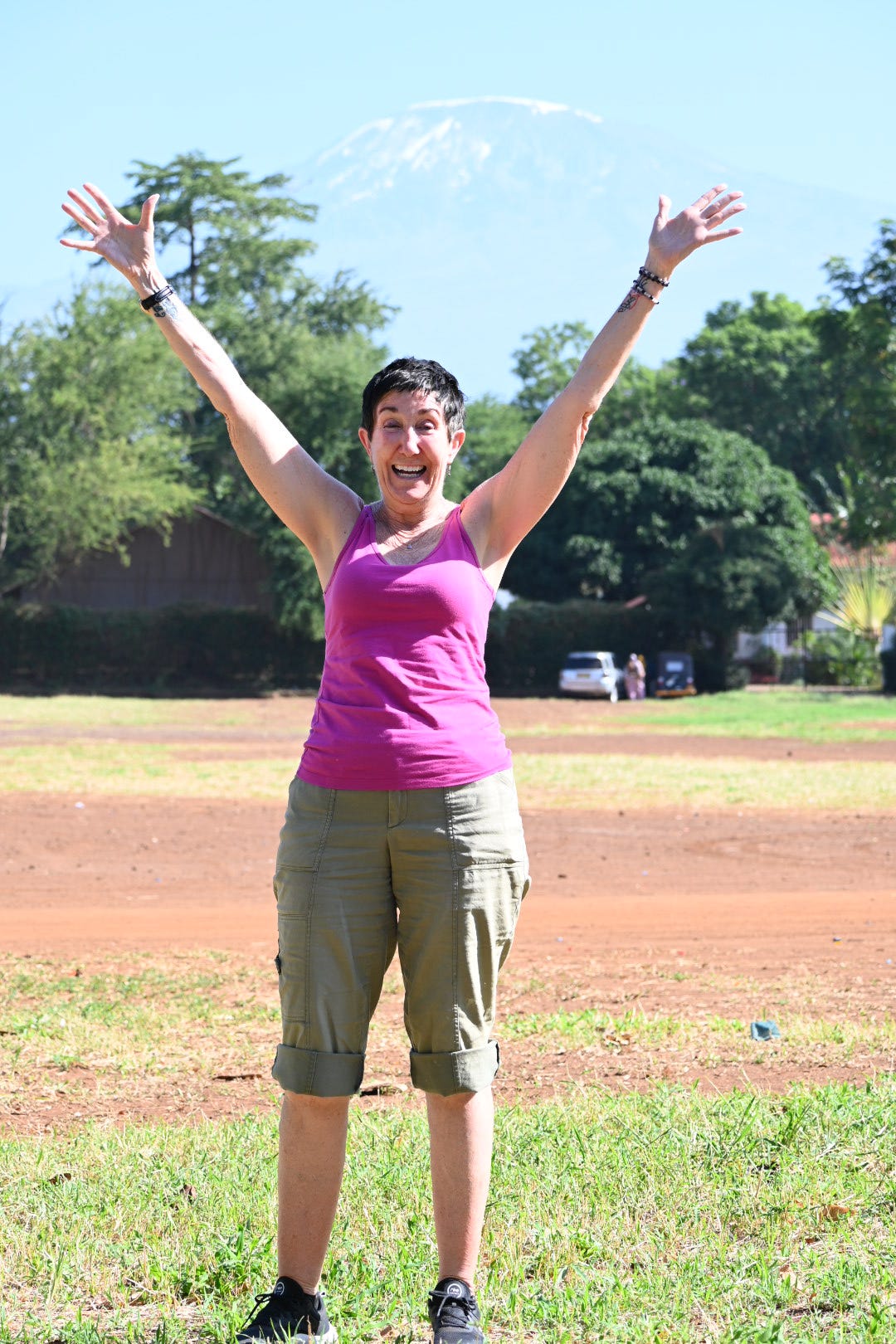 Happy traveller with Mount Kilimanjaro in the background during a Go Vision Safaris Tanzania journey