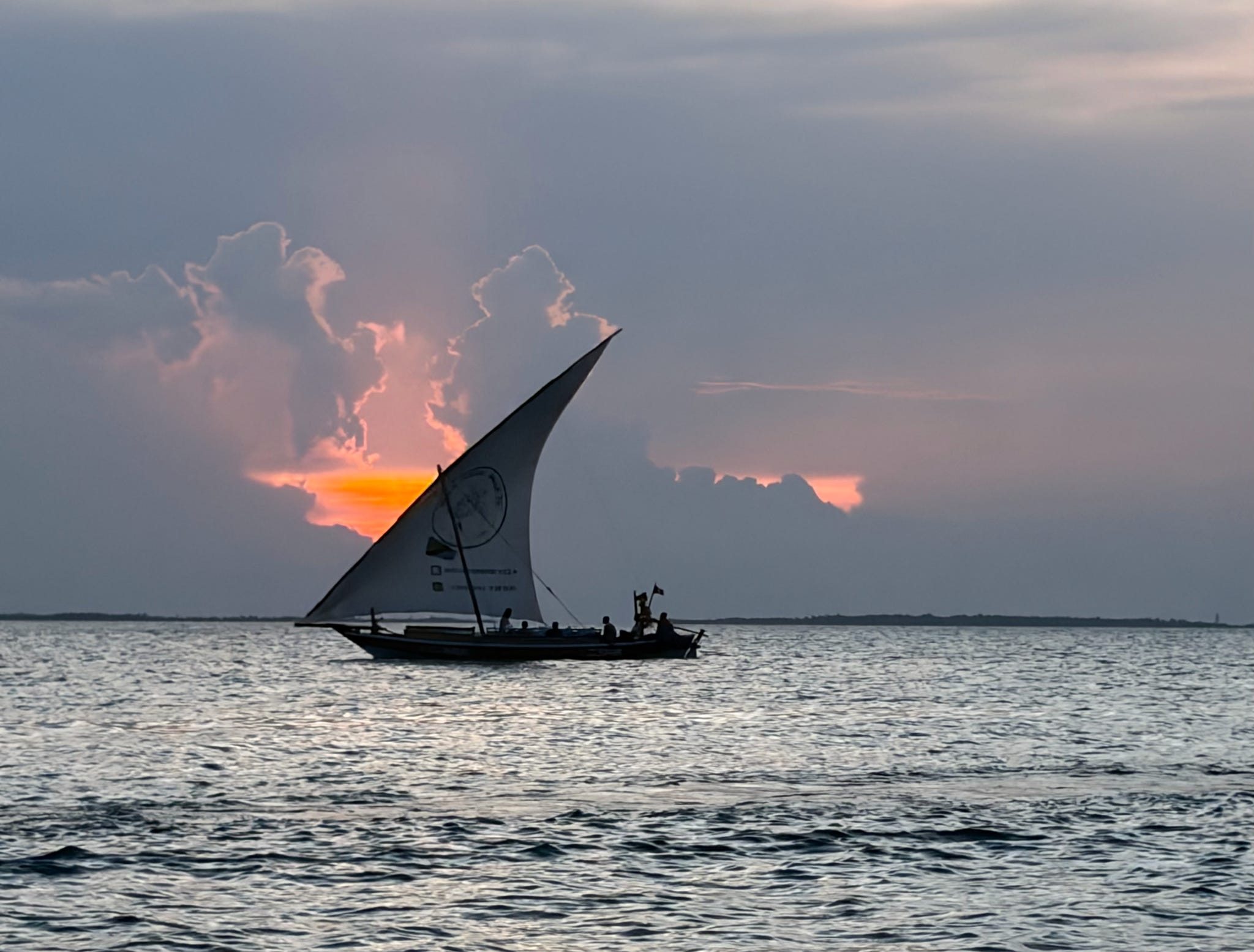 Traditional Zanzibar dhow sailing on the Indian Ocean during sunset in Tanzania